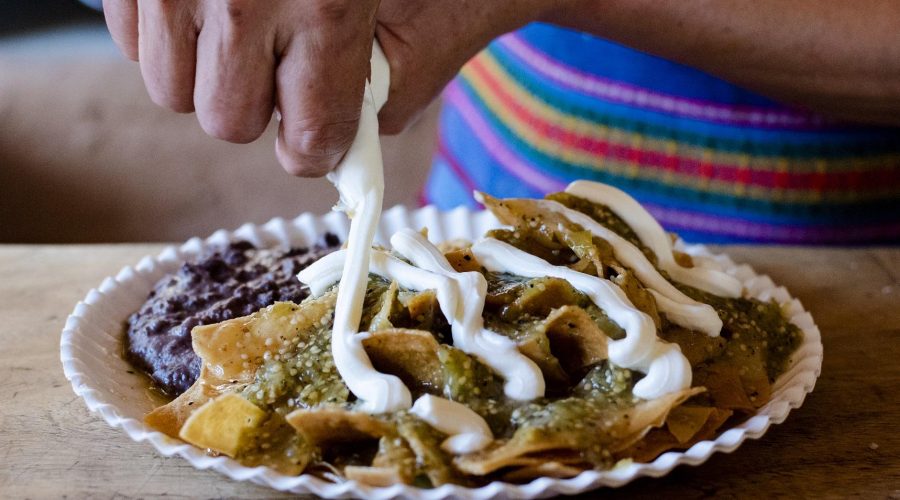 Green Chilaquiles being garnished with crema on top